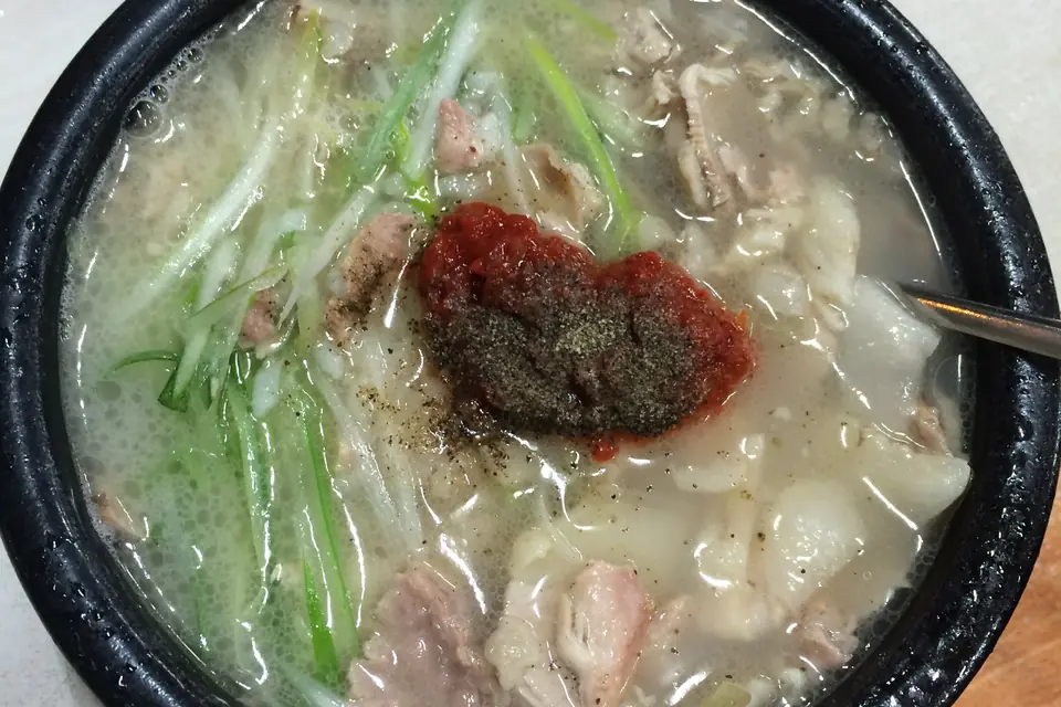 Dwaeji gukbap with a spoonful of red chilli paste and black pepper on top of the pork and spring onions. Similar to a Busan bowl, not from a shop named on this page.