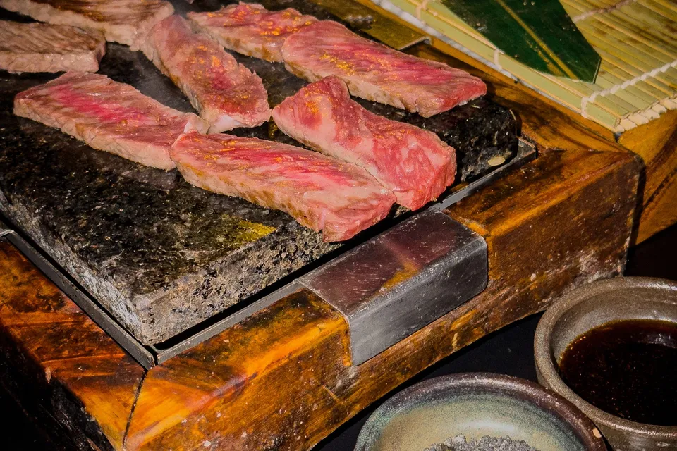 Sliced beef on a hot stone plate, similar to the stone a gyukatsu cutlet is finished on, and not taken at the restaurant