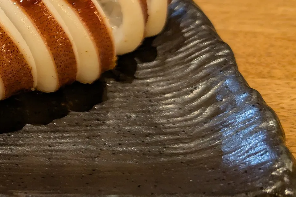 Close view of grilled squid at a stall in Nishiki Market, Kyoto. A sign at the edge of the original frame is cropped out.