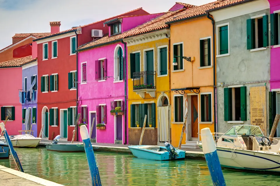 Brightly painted houses and small boats along a canal on Burano, Venice