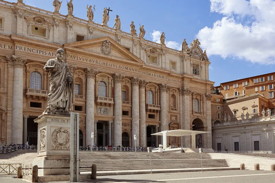 The facade of St Peter's Basilica in Vatican City, with a statue of St Peter in front