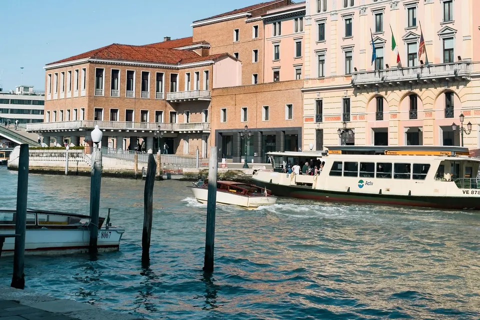A vaporetto water bus passing pastel buildings on the Grand Canal in Venice on a sunny day