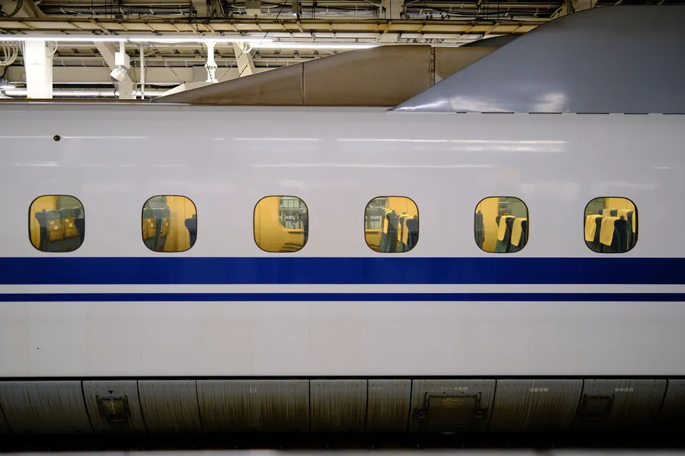 The side of a shinkansen bullet train at Tokyo Station, with passengers visible through its windows