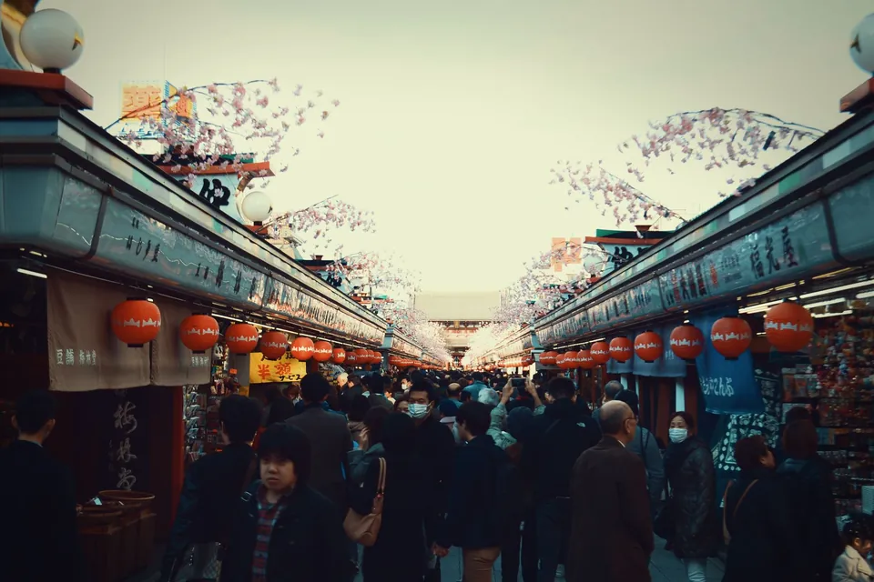 A busy Tokyo shopping street lined with red lanterns and spring blossom decorations