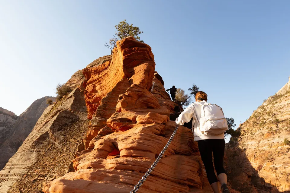 Hikers holding the chains on the sandstone ridge up to Angels Landing in Zion National Park