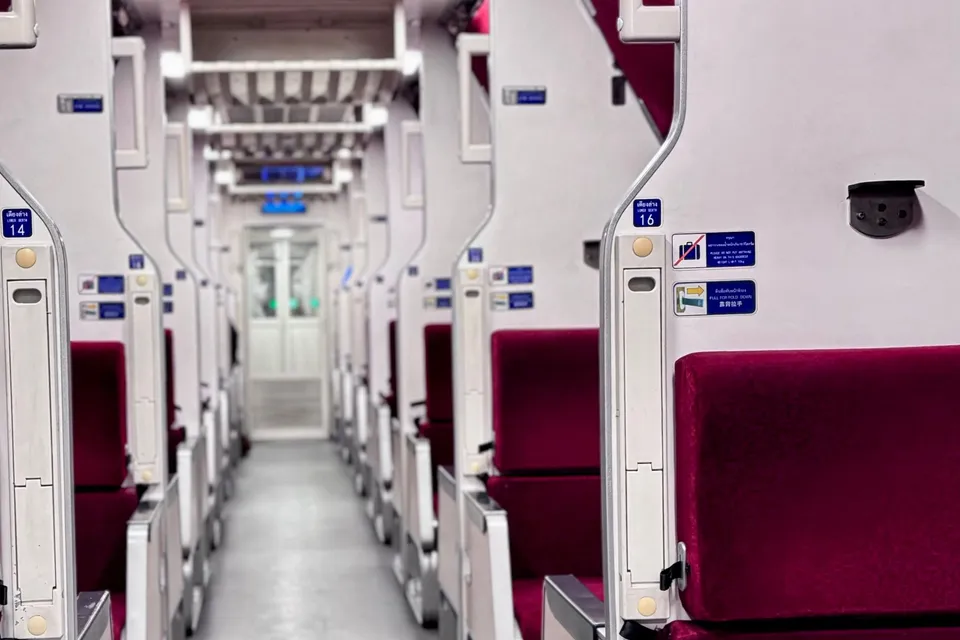 The aisle of a newer Thai sleeper car, with red seats that are made up into berths at night