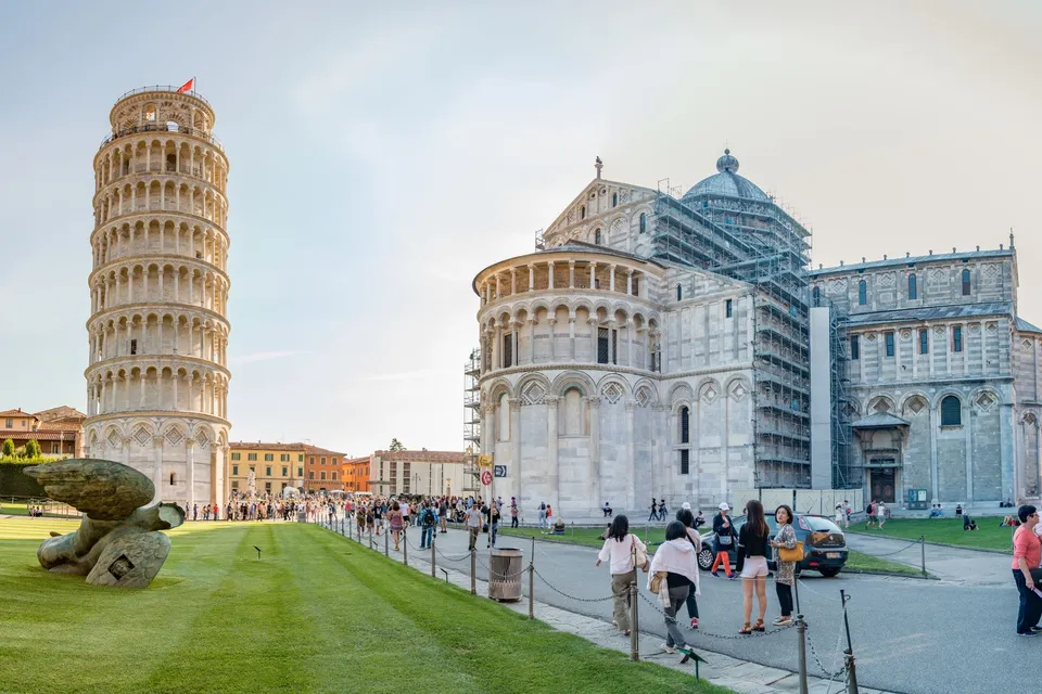 The Leaning Tower of Pisa beside the cathedral, with visitors crossing the Piazza dei Miracoli