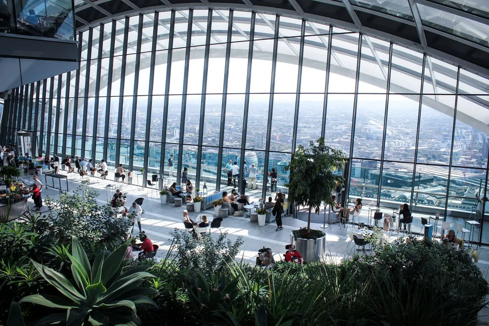 Visitors among the plants and the glass walls of the Sky Garden in London, high above the city